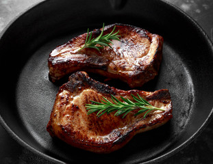 Cooked Pork Loin chops in rustic skillet, pan with rosemary.