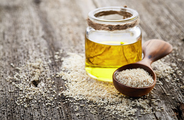 Obraz na płótnie Canvas Sesame oil with seeds on wooden background