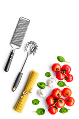 Preparing to cook pasta. Spaghetti, tomatoes, garlic, cheese grater, spoon for spaghetti on white background top view copy space