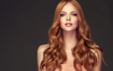 Photo sur Aluminium Salon de coiffure Fille rousse aux cheveux ondulés longs et brillants. Belle femme modèle avec une coiffure frisée.