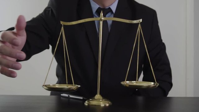 justice and law concept.Male lawyer in the office with brass scale on wooden table