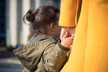 Small kid holding mother's hand.