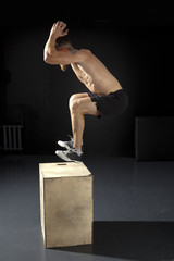 Man jumping on fit box in gym