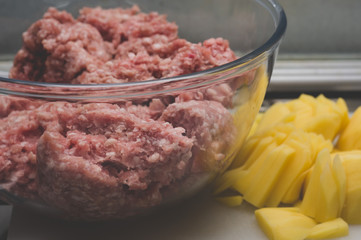 Sliced potato for soup and meat stuffing for making meatballs. Soup with meatballs and pasta prepear in process.
