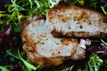 fried meat with salad, herbs, pepper on a dark wooden background. Background for the postcard.