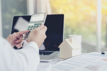 Business people use the computer laptop to calculate the interest on the loan, and the tax on a purchase-sale of real estate