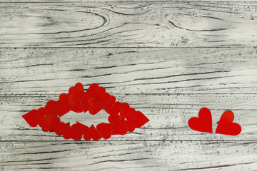 Lips of little red hearts on a wooden background. The concept of Valentine's Day.