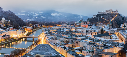 Naklejka premium Widok na oświetlone stare miasto Salzburga w zimowy poranek