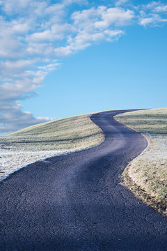 gewundene Stra&szlig;e auf den H&uuml;gel, frostige Landschaft und blauer Himmel