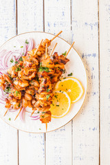 Chicken kebab with a lemon and onion on a wooden background.