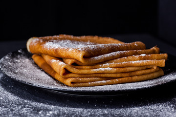 Stack of crepes with powdered sugar on dark background. Maslenitsa. Russian folk festival - 189070394