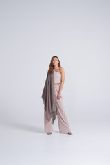 Fashionable woman in trendy clothing and scarf posing in studio