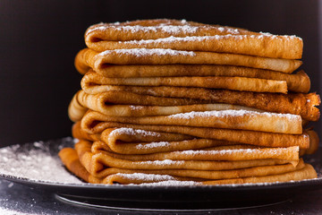 Stack of crepes with powdered sugar on dark background. Maslenitsa. Russian folk festival - 189070708