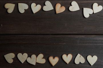 Little wooden hearts on brown wooden background