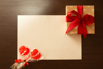 beautiful decorated gift in a box with a red bow and lollipops on a wooden dark background