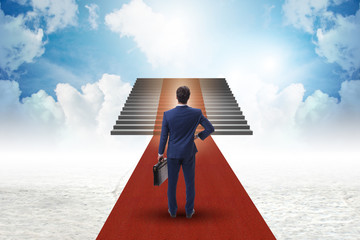 Obraz na płótnie Canvas Young businessman climbing stairs and red carpet into sky