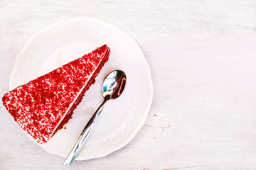 triangle slice red berry cake top view on the white dish with spoon on the white wooden table