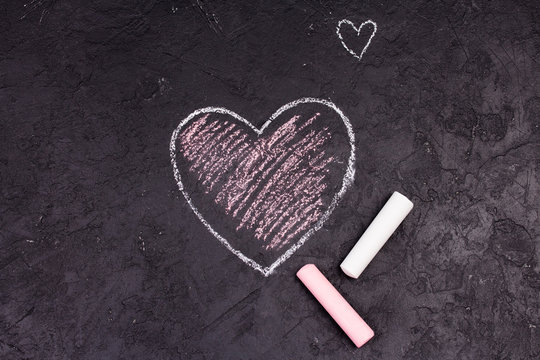 Chalk drawing of pink heart on the blackboard.