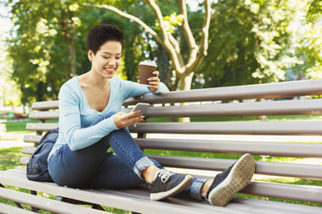 Young smiling woman using smartphone outdoors