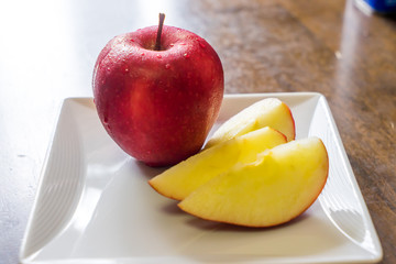Sliced fresh red apple on a white square dish