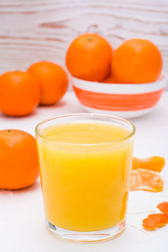 Mandarin juice in a glass and ripe mandarins on a table