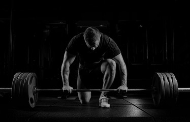 Professional athlete bent over the barbell and is preparing to lift a very heavy weight.