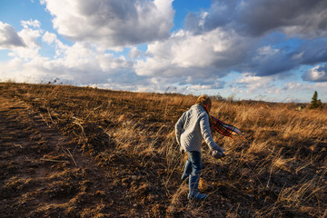 Boy walking through a field on a windy day