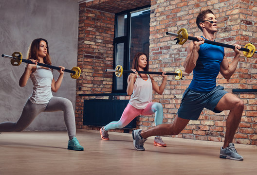 One man and two women doing squats.