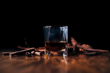 Close-up of a glass of whisky with cinnamon sticks on a table