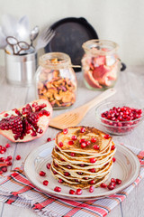 A pile of pancakes with pomegranate seeds on a plate