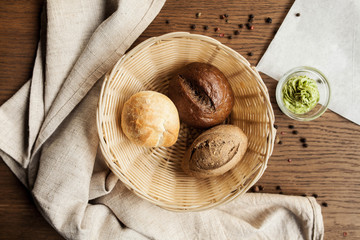 a wooden basket with different buns and bread on a wooden table - 189078774
