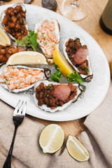 beautiful presentation of different types of tartar in oyster shells on ice with lemon