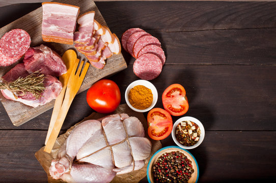 Chicken carcass, meat and delicacies on a wooden table. Dark background, top view.