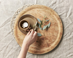 Hand arranging a candle and simple decor with leaves