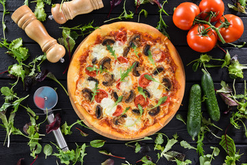 Flatlay of healthy vegetable mushroom pizza served with fresh vegetables, greens, pizza cutter and...