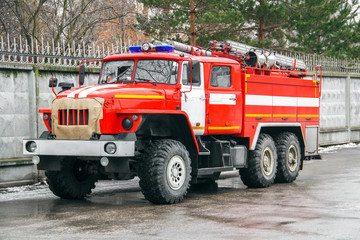 The fire truck in full equipment rushes to a challenge along the asphalt road next to the concrete...