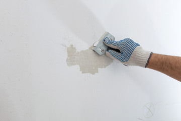 Worker removes old paint from concrete wall with scraper - obrazy, fototapety, plakaty