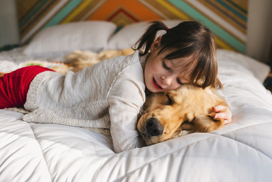 Girl lying on a bed with her golden retriever dog