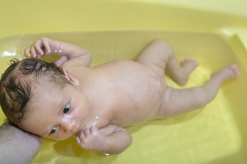 Small baby first bathing on mothers hands