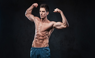 Shirtless muscular male over dark background.