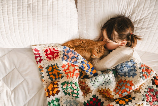 Girl having a nap on a bed with her cat