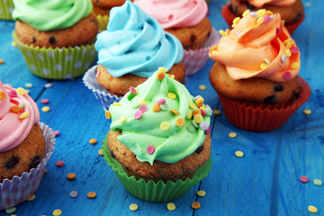 Tasty cupcakes on wooden background. Birthday cupcake in rainbow colors