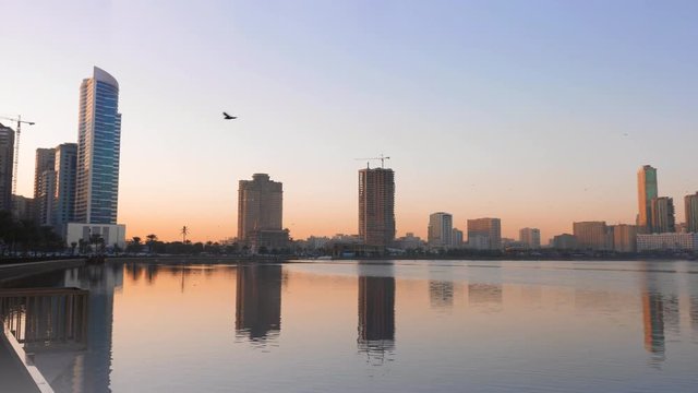 Beautiful Khalid Lagoon at sunrise morning. Cityscape scene with birds, lake and skyscrapers.