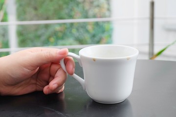 Hand Holding Empty Cup of Coffee on The Table