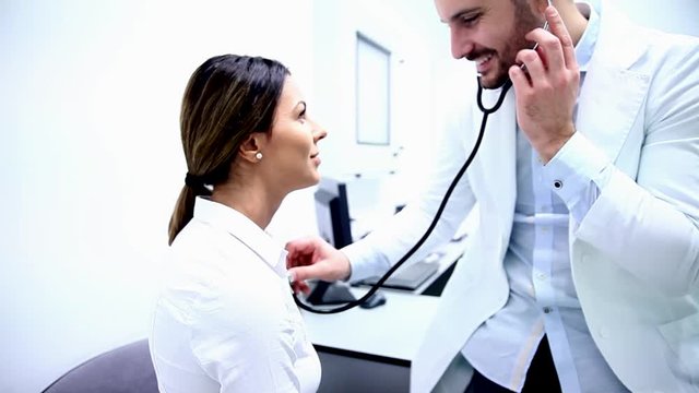 Doctor examining young woman by stethoscope