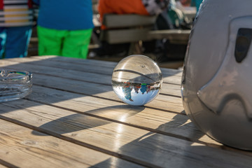 Glass ball on a wooden table in the Dolomites. A view across the globe around us. Sunny day in Dolomites. Alpe di Lusia.. Italy