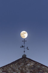 Fototapeta na wymiar Full moon backlit, over Sant Joan de Caselles Church built in the 11-12th century, in Canillo village. Andorra.