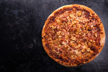 Top view of fresh baked pizza on dark wooden background with copy space available