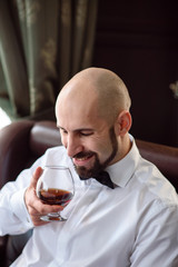 A brutal man tasting cognac.