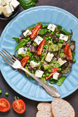 Vegetarian salad with blue cheese, tomatoes, green peas and sesame on a concrete background.